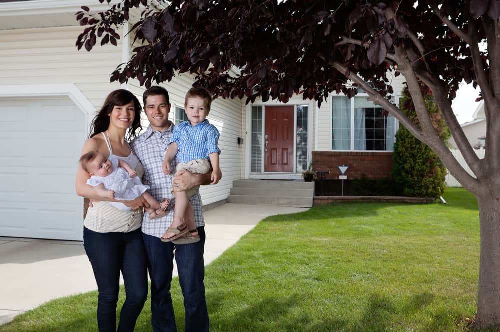 65 MjAxMS0wOC0xNS0xMDM2LTI0LmpwZw== Portrait d'un couple heureux debout avec leurs enfants devant une maison